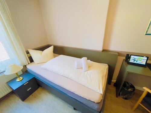 a small bedroom with a bed with two towels on it at Hotel Schnehagen in Bad Fallingbostel