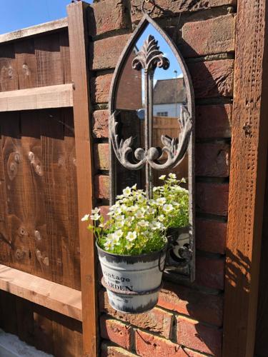 a potted plant on a brick wall with a mirror at Corner Cottage - character, charm, great location. in Ringwood