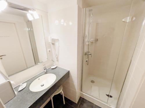 a bathroom with a sink and a shower at Hotel Schnehagen in Bad Fallingbostel