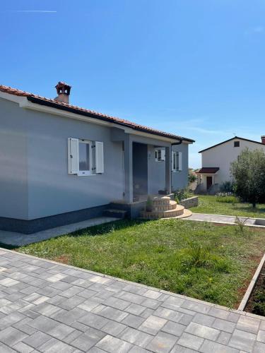 a small white house with a grass yard at Holiday Home Mihaela in Višnjan