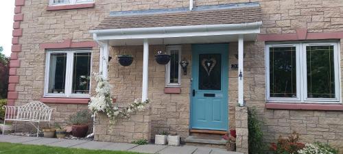 una casa de ladrillo con una puerta azul y un banco en Homely Haven, Dunfermline, en Dunfermline