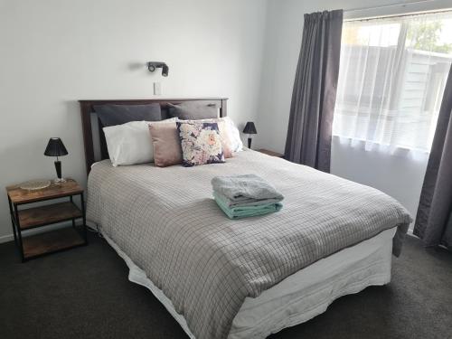 1 dormitorio con 1 cama grande con almohadas y ventana en Cambria Hideaway en Nelson