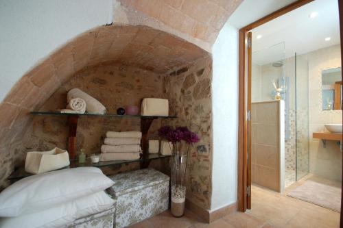 baño con pared de piedra, cama y ducha en Lets Holidays Tossa de Mar Romantic Apartment, en Tossa de Mar