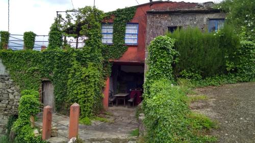 een oud huis bedekt met klimop met een tafel bij RIBEIRA SACRA La Imperfecta in Ferreira