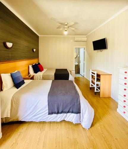 a bedroom with two beds and a flat screen tv at Costa Brava Alojamento in Benedita