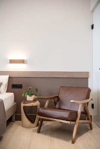 a brown leather chair in a bedroom with a bed at Esperides Beach Hotel Apartments in Stalos