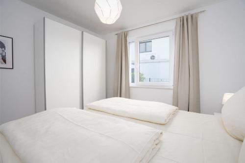 1 dormitorio blanco con 2 camas y ventana en Kiepenberg-9a-Scharbeutz-Kie-009, en Scharbeutz