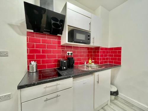 cocina con fregadero y pared de baldosas rojas en Comfortable - Cosy - Budget Studios in City Center, en Londres