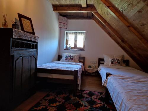 a attic room with two beds and a window at Bobića konak - Lukomir in Lukomir