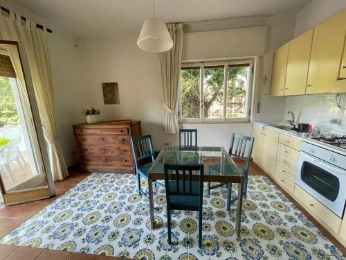 una cucina con tavolo in vetro e sedie su un tappeto di Casa Mirtina Ischia Sea House a Ischia