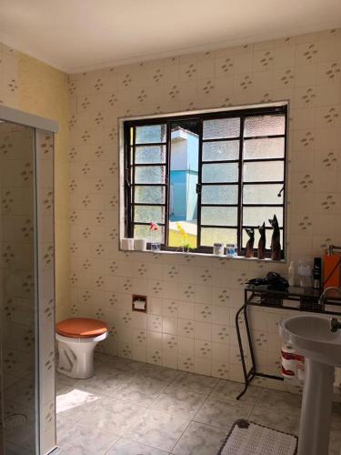 a bathroom with a toilet and a window at Prainha Pousada - Bar e Restaurante in Itanhaém