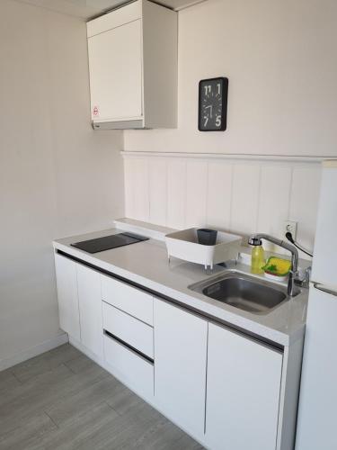 a kitchen with white cabinets and a sink at Yeosu Blooming Pension in Yeosu