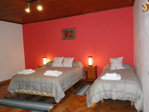 1 dormitorio con 2 camas y pared roja en Hospedaje Amilcar en Esquel