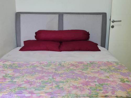 Una cama con dos almohadas rojas encima. en Apartemen Springlake Summarecon Bekasi-By Bu Johan en Bekasi