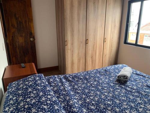 um quarto com uma cama azul e uma colcha azul e branca em Apartamento tipo boutique por el CC Titán Plaza em Bogotá