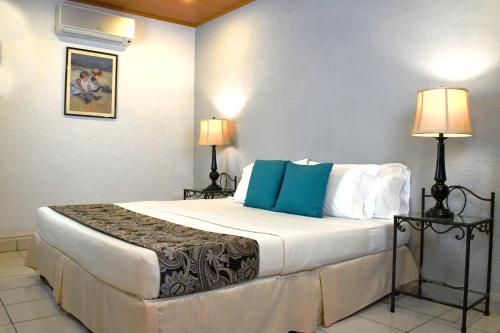 a hotel room with a large bed with blue pillows at Hotel San Jose, Matagalpa. in Matagalpa