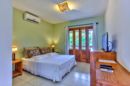 una camera da letto con un letto, una scrivania e una televisione di Barcaça Pousada a Itacaré