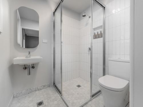 a bathroom with a shower and a toilet and a sink at Chalet Alpina in Jindabyne
