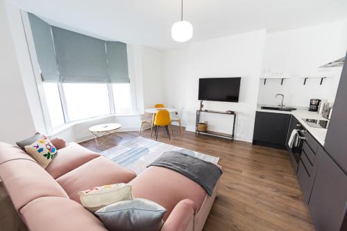 a living room with a pink couch in a kitchen at Coastline Villas - Heart of Redcar 1 & 2 Bed Apartments, ideal for contractors and holidayers in Redcar