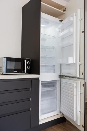 a kitchen with an empty refrigerator and a microwave at Coastline Villas - Heart of Redcar 1 & 2 Bed Apartments, ideal for contractors and holidayers in Redcar