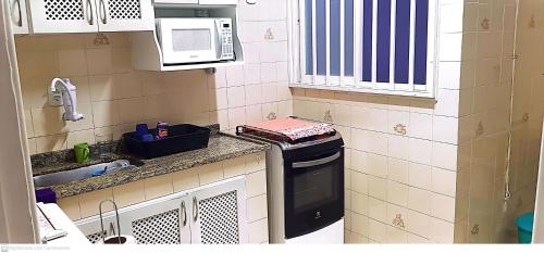 uma pequena cozinha com fogão e micro-ondas em Apartamento Cabo Frio 2 QUARTOS 250 METROS DA RODOVIÁRIA em Cabo Frio
