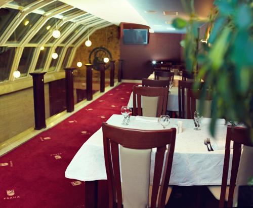 a dining room with white tables and chairs and a red carpet at Hotel Praha in Uzhhorod