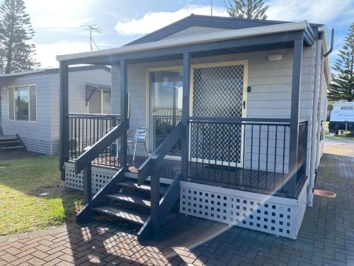 a tiny house with a staircase leading to a porch at Christies Beach Tourist Park in Christies Beach