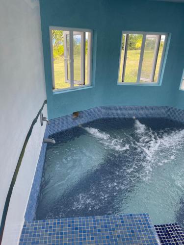 a pool of water in a bathroom with two windows at ‘MORIAH’ Private Room with Double Bed and shared bathroom in Saint Philip