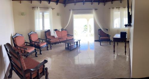 a waiting room with chairs and a table and a piano at ‘MORIAH’ Private Room with Double Bed and shared bathroom in Saint Philip