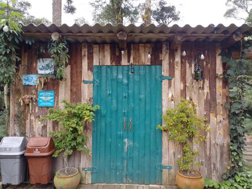 a green door on a wooden fence with two plants at Bangalô dos Alpes de São Chico in São Francisco de Paula