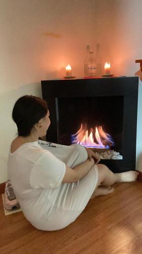 a woman sitting in front of a fireplace at Cabañas el Olimpo in Aquitania