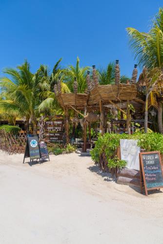 a restaurant on the beach with palm trees at Hotel Villas Tiburon Adults Only in Holbox Island