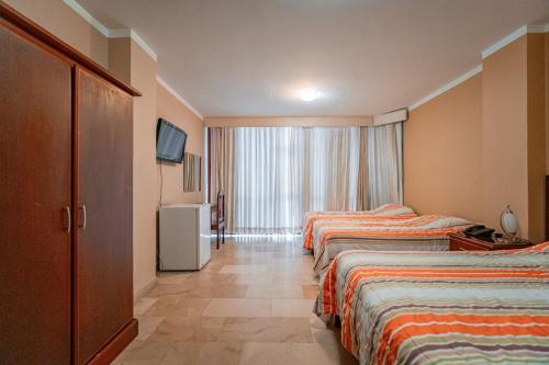 Habitación de hotel con 2 camas y TV en Sol Del Sur Hotel en Huaquillas