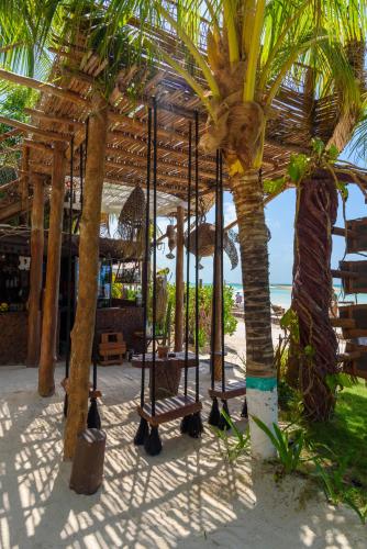 a swing on the beach next to palm trees at Hotel Villas Tiburon Adults Only in Holbox Island