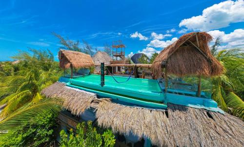 a blue boat with straw roofs and palm trees at Hotel Villas Tiburon Adults Only in Holbox Island