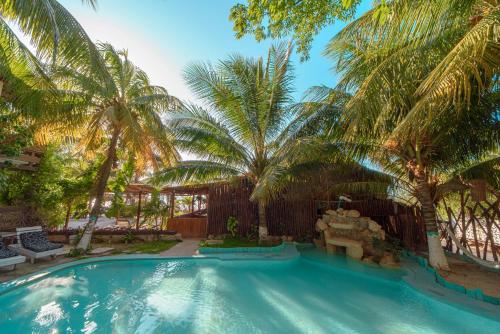 a swimming pool with palm trees in a resort at Hotel Villas Tiburon Adults Only in Holbox Island