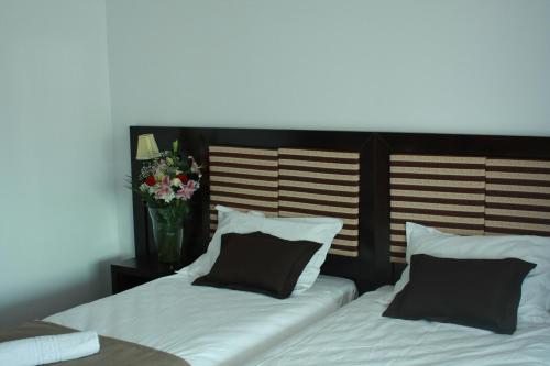 two beds with black and white pillows and a vase of flowers at Pensiunea Clasic in Curtea de Argeş