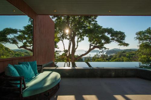 a room with a chair and a large window at Sri Panwa Phuket Luxury Pool Villa Hotel - SHA Plus in Panwa Beach