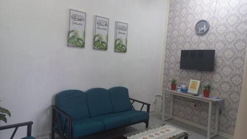 sala de estar con silla azul y TV en BenBahrains Homestay - PB - ISLAMIC COMPLIANCE ONLY, en Masjid Tanah