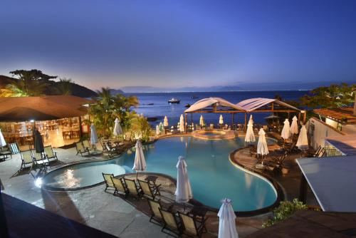 Blick auf einen Pool mit Sonnenschirmen und Stühlen in der Unterkunft Hotel La Forêt & Beach Club in Búzios