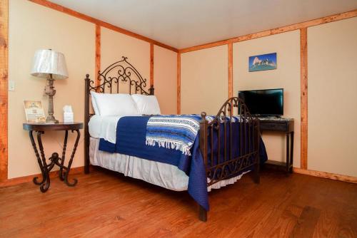 a bedroom with a bed and a desk with a television at Coyote Station Lodging in Round Top