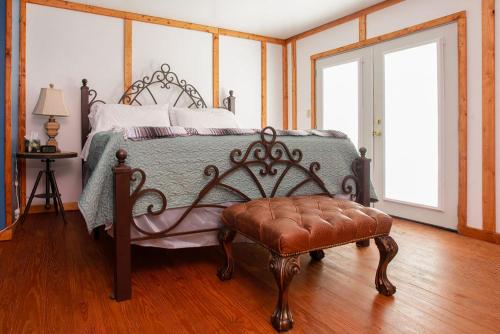 a bedroom with a bed with a bench and two windows at Round Top Hotel in Round Top