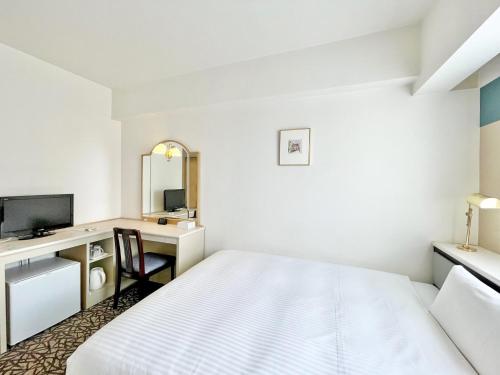 een slaapkamer met een bed en een bureau met een spiegel bij Chisun Hotel Yokohama Isezakicho in Yokohama