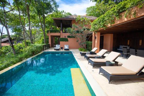 a swimming pool with lounge chairs and a house at Sri Panwa Phuket Luxury Pool Villa Hotel - SHA Plus in Panwa Beach
