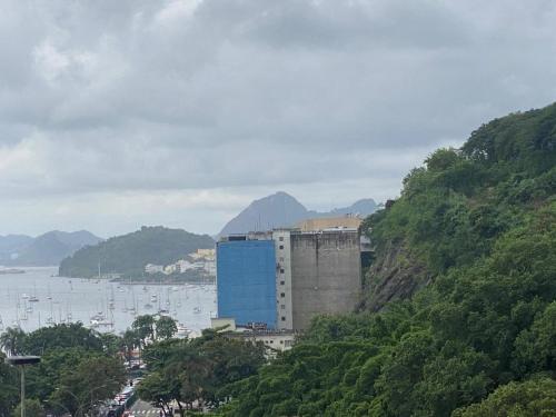 里約熱內盧的住宿－Botafogo Suites，水体旁的山丘上的蓝色建筑
