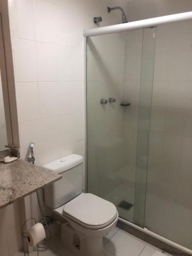 Un baño con inodoro y ducha de cristal. en Mandai 01 suíte APT 311 MC temporadas, en Cabo Frío