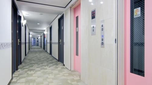 a corridor of a hospital hallway with pink walls and floors at Toyoko Inn Kenkyu-gakuen Ekimae in Tsukuba
