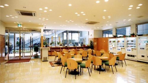 un restaurant avec des tables et des chaises dans un bâtiment dans l'établissement Toyoko Inn Shin-yokohama Ekimae Shinkan, à Yokohama