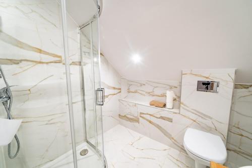 La salle de bains est pourvue d'une douche et de toilettes. dans l'établissement Apartamenty i pokoje Seeblick, à Mikołajki