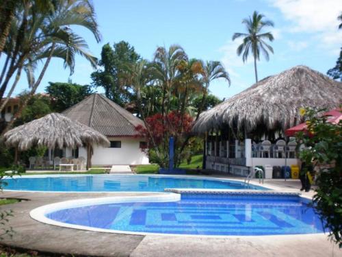 a swimming pool in front of a resort with palm trees at Hotel Maribu Caribe in Puerto Limón